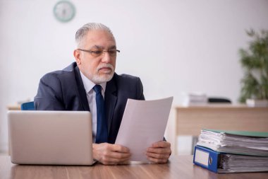 Old employee sitting at workplace