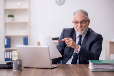 Old employee sitting at workplace