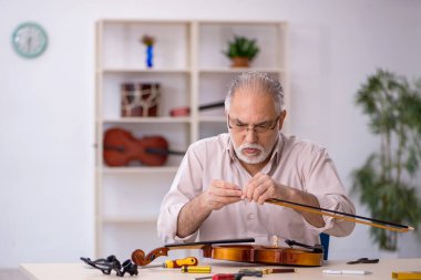 Eski tamirci atölyede müzik aletlerini tamir ediyor.