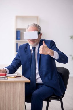 Old businessman employee wearing virtual glasses in the office