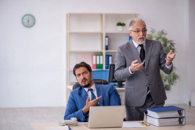 Eski patron ve genç çalışan işyerinde çalışıyor.