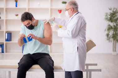 Yaşlı erkek doktor genç hastaya hediye kutusu veriyor.