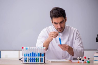 Sınıfta oturan genç kimyacı öğretmen.