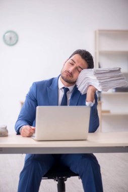 Genç işadamı ve işyerinde çok fazla iş var.