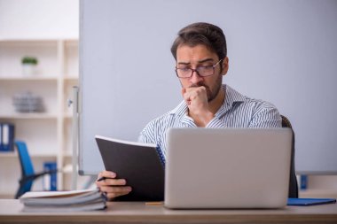 Genç öğretmen sınıfta oturuyor.