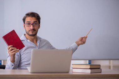 Genç öğretmen sınıfta oturuyor.