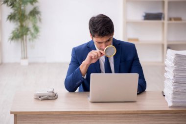 Young auditor holding loupe at workplace