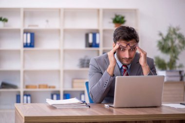 Genç işadamı işyerinde oturuyor.