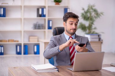 Genç işadamı işyerinde oturuyor.