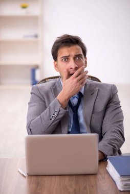 Genç işadamı işyerinde oturuyor.