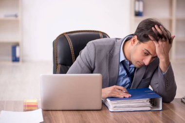 Genç işadamı işyerinde oturuyor.