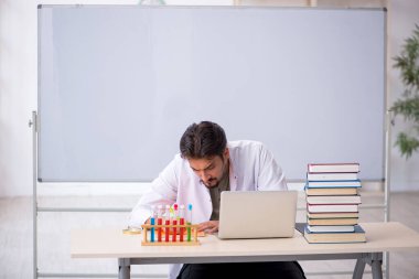 Genç kimyacı öğretmen beyaz tahtanın önünde.