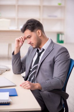 Genç işadamı işyerinde oturuyor.