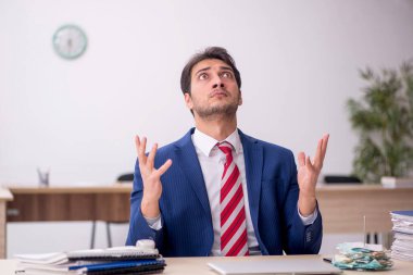 Genç erkek çalışan işyerinde oturuyor.