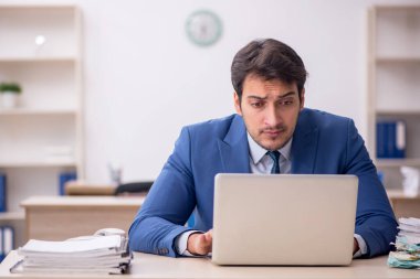 Genç erkek çalışan işyerinde oturuyor.