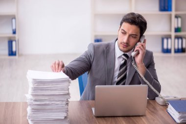 Genç bir çalışan ve ofiste çok fazla iş var.