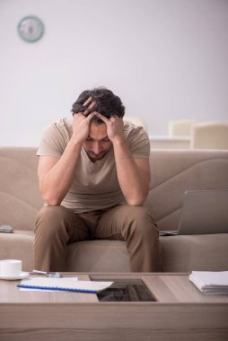 Genç erkek çalışan salgın sırasında evden çalışıyor.