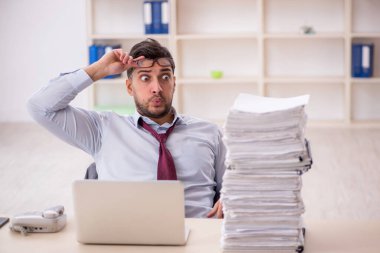 Young employee and too much work at workplace