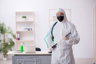 Young contractor disinfecting office during pandemic