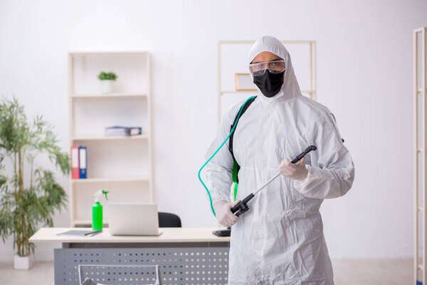 Young contractor disinfecting office during pandemic