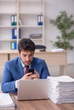 Young employee and too much work at workplace