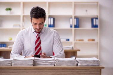 Genç işadamı ve işyerinde çok fazla iş var.