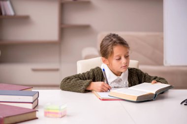 Küçük kız evde ders çalışıyor.