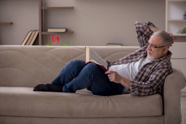 Old man reading book at home during pandemic