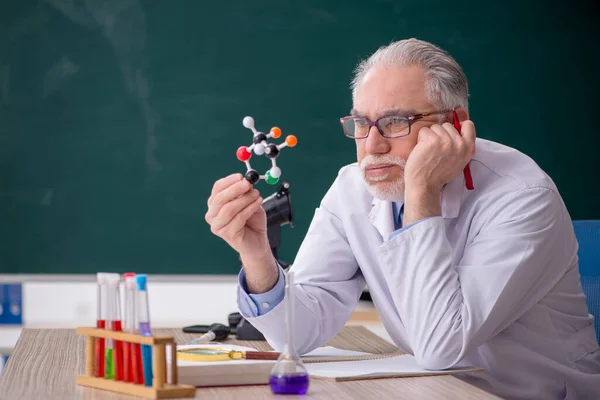 Old chemist teacher sitting in the classroom