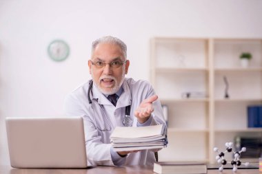 Klinikte çalışan yaşlı bir doktor.