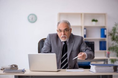 İş yerinde oturan yaşlı erkek çalışan.