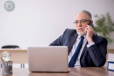 Old employee sitting at workplace