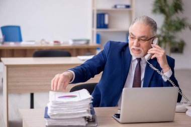 Old employee sitting at workplace
