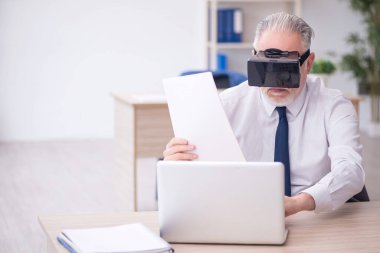 Old businessman employee wearing virtual glasses in the office