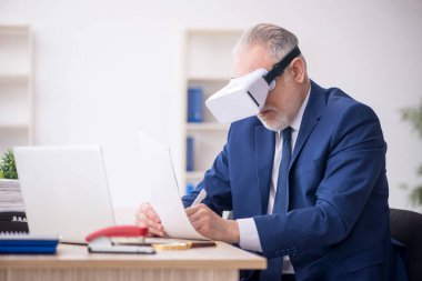 Old businessman employee wearing virtual glasses in the office