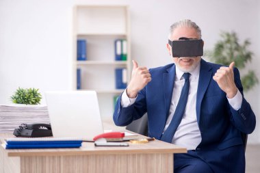 Old businessman employee wearing virtual glasses in the office