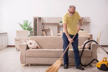 Yaşlı adam evi temizliyor.