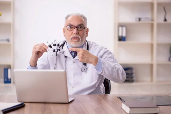 Old doctor studying molecular model in the clinic