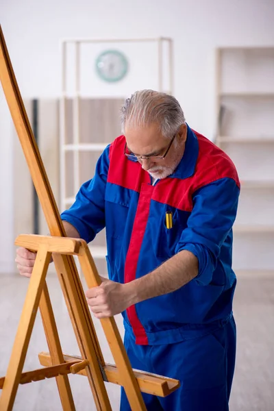 Old carpenter repairing drawing easel