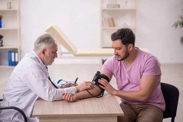 若い患者の血圧を測定する古い医師 — ストック写真