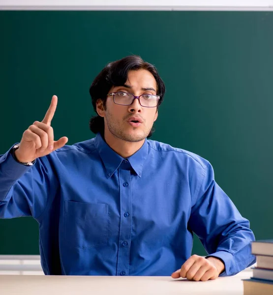The young male teacher in front of chalkboard