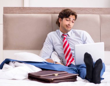 Evde çalışan genç bir çalışan yatakta oturuyor.