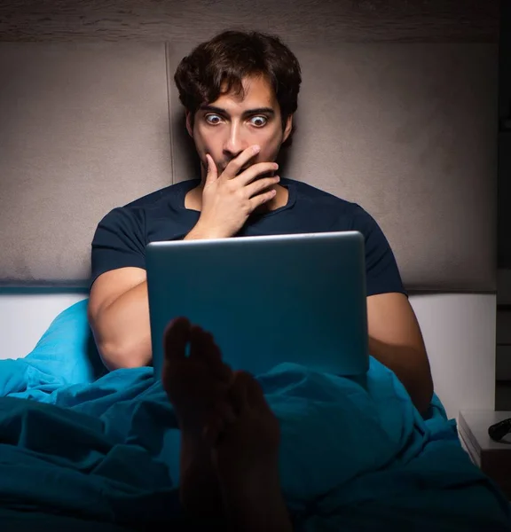 The man working on laptop at night in bed