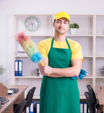 Genç erkek müteahhit ofisi temizliyor.