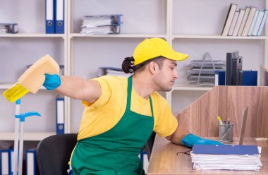 Genç erkek müteahhit ofisi temizliyor.