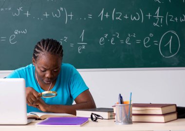 Kara tahtanın önündeki siyah kız öğrenci.