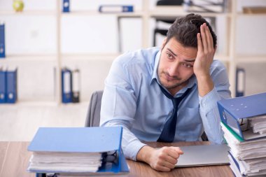 Young employee and too much work at workplace