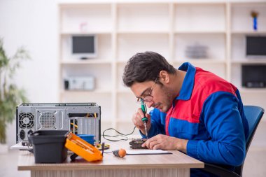 Atölyede bilgisayar tamir eden genç bir tamirci.