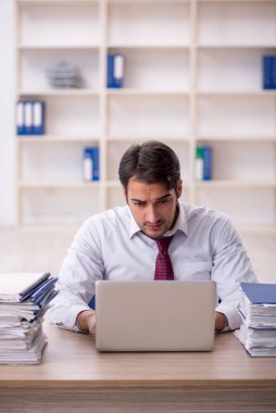 Genç işadamı ve işyerinde çok fazla iş var.