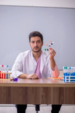 Young chemistry teacher sitting in the classroom